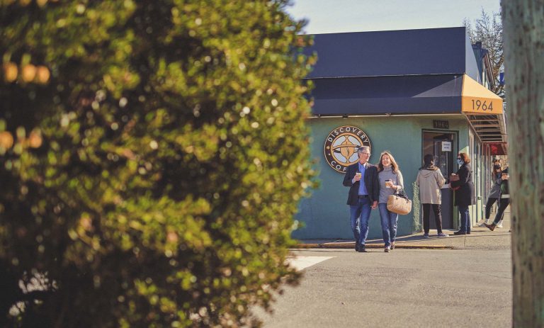 A man and woman walk, holding hands.