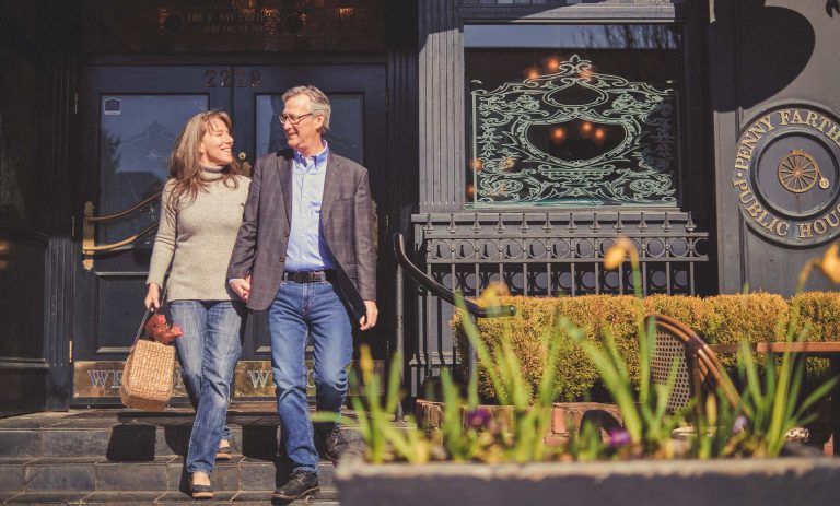 A man and woman walk, holding hands.